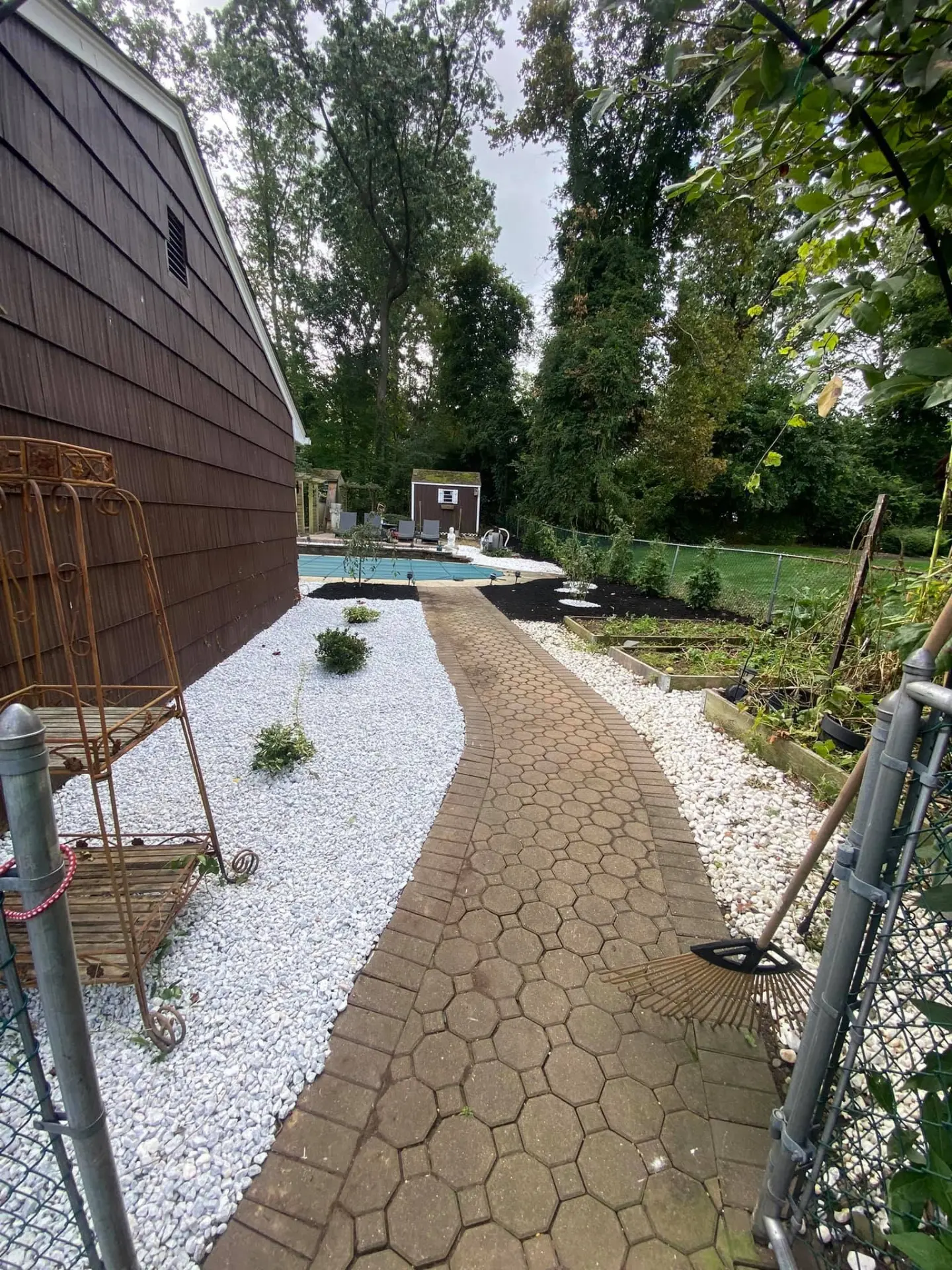 Paver path with white stone beds leading to a backyard pool