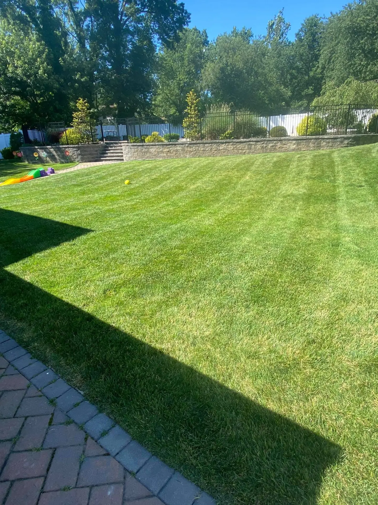 Block retaining wall terrace above a healthy striped backyard lawn