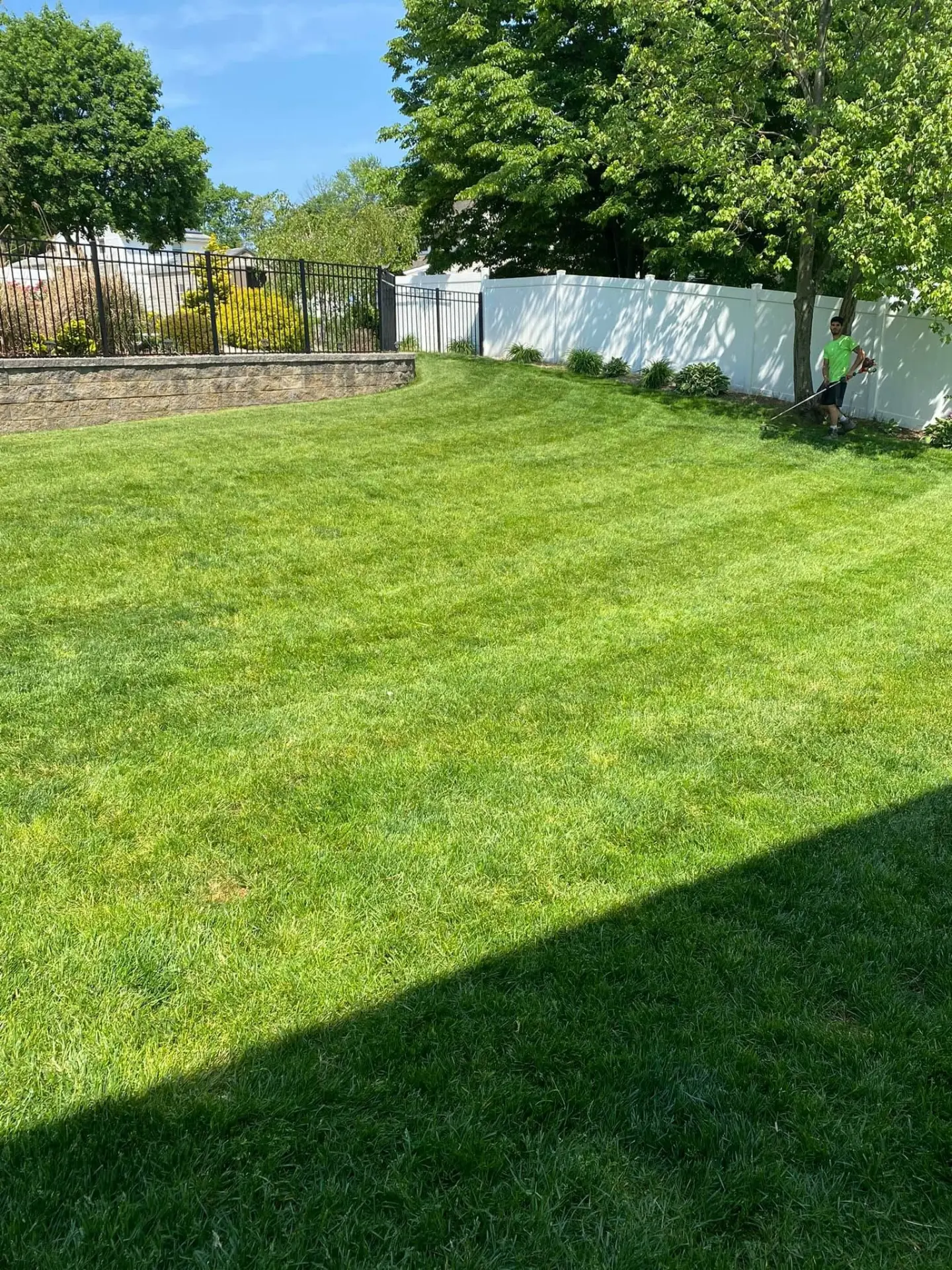 Fiorenza Landscaping crew member trimming edges of a large fenced lawn