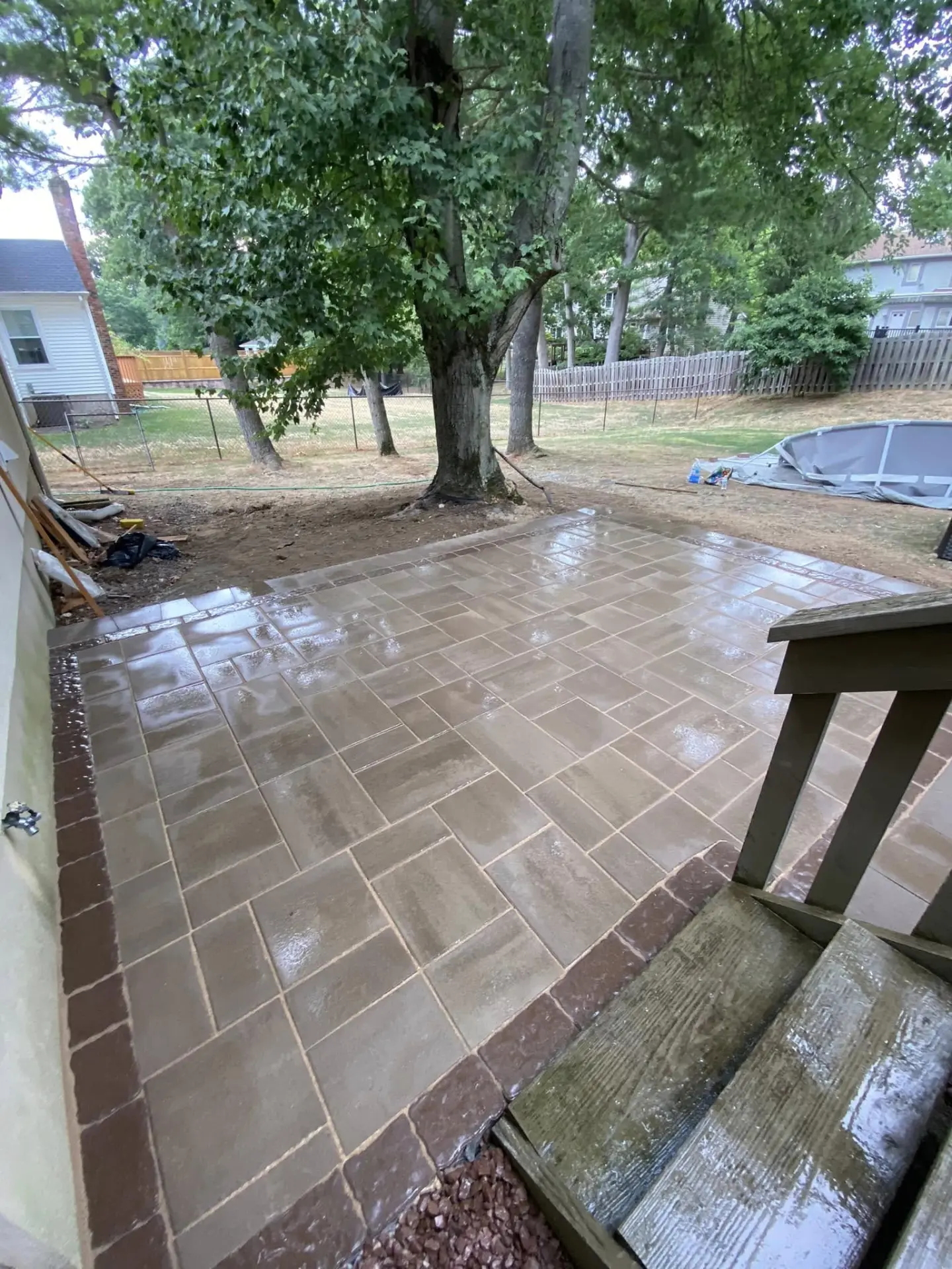 Finished backyard paver patio with a contrasting border by Fiorenza Landscaping