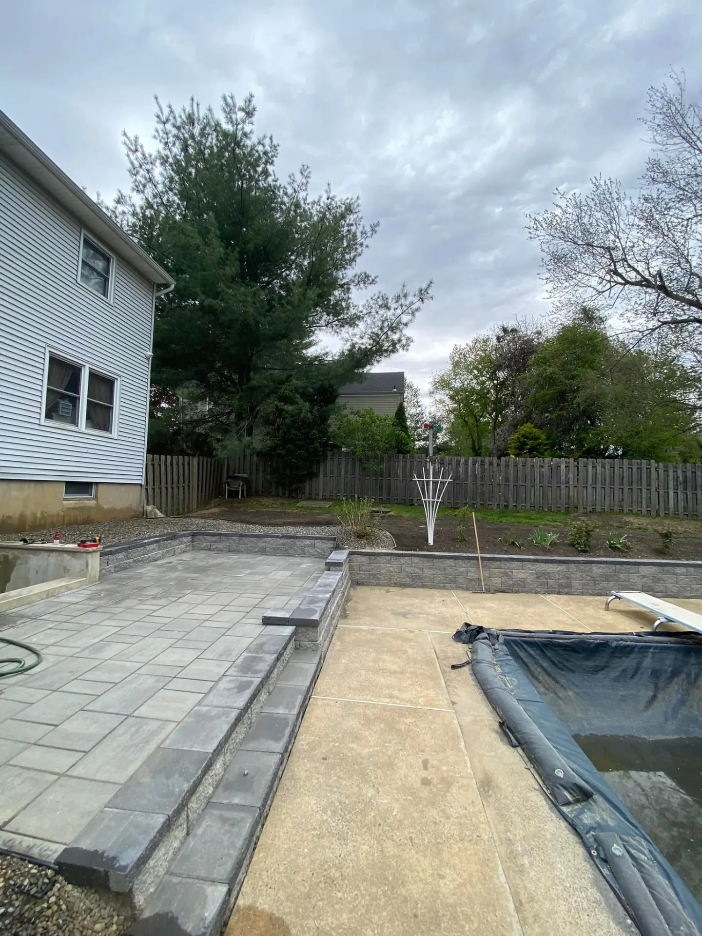 Paver patio with block retaining wall beside a backyard pool