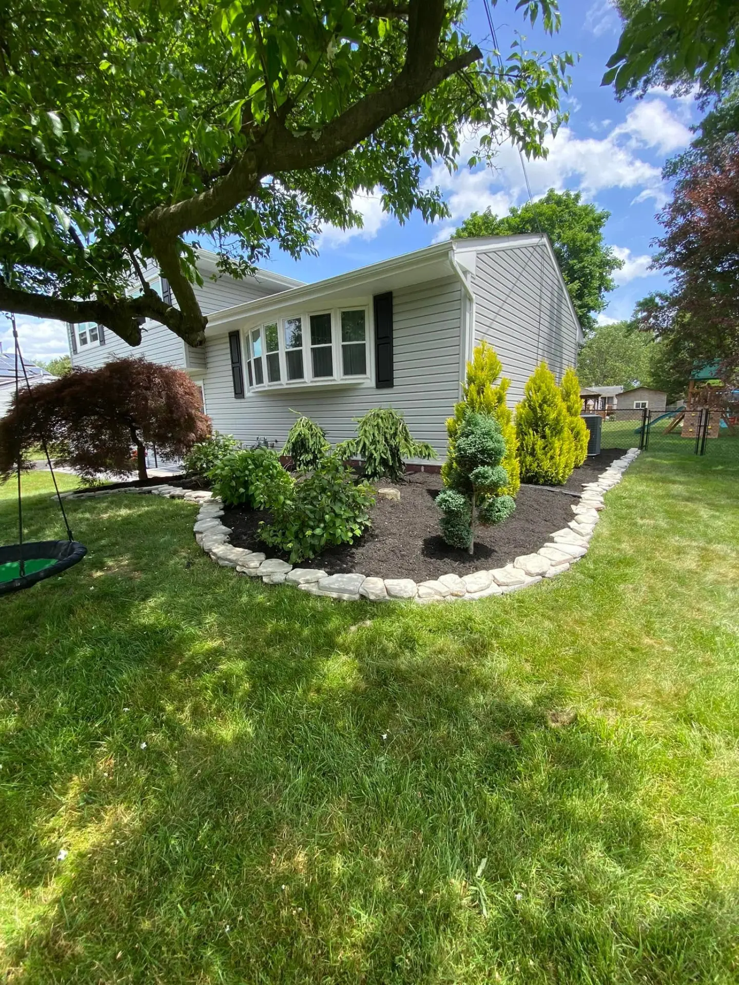 Curved stone edging around a fresh mulch bed with new shrubs
